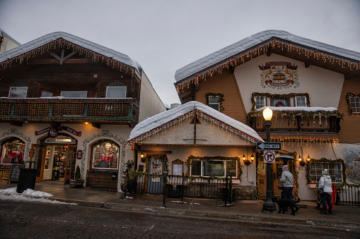 Street and buildings with Christmas lighting decoration in winter in Bavarian themed town of Leavenworth, Washington, USA. Tourists walking at the store front on the main street.