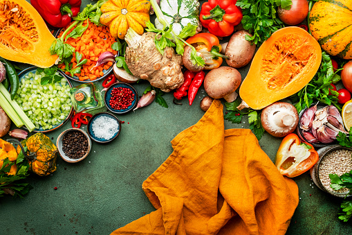 Food background. Vegetables, mushrooms, roots, spices - ingredients for vegan, cooking. Orange kitchen towel. Healthy eating, diet, comfort slow food. concept. Rustic table, top view
