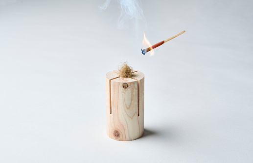 Hand holding a burning match, isolated on black background