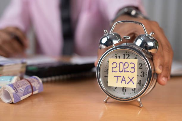 istock businessman placing timer with 2023 tax while calculating financial bills at office table - concept of financials and investment 1457287497