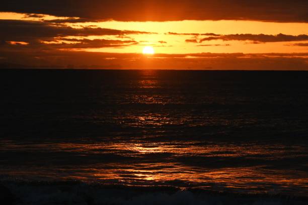 istock The beach at dawn when the sun's rays dye the waves red. 1457292047