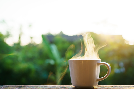 Beautiful sunrise lighting in the morning with a hot coffee and Moka Pot close up with copyspace. Beautiful natural sun lighting bokeh and coffee cup in the morning.