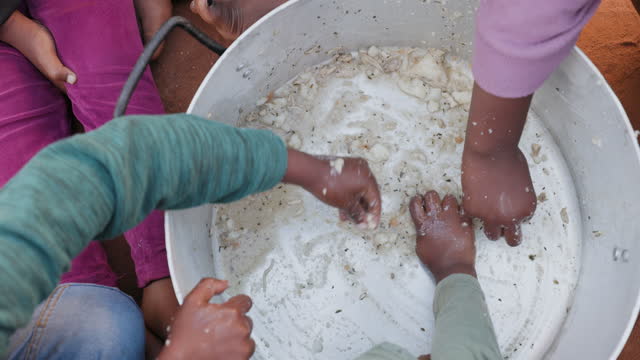 Poverty in Africa. Small group of starving Black African children scraping food from the bottom of a communal cooking pot