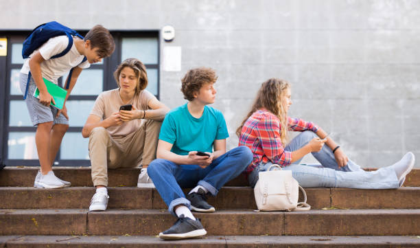 istock Teens with smartphones on stairs beside shool building 1457294853
