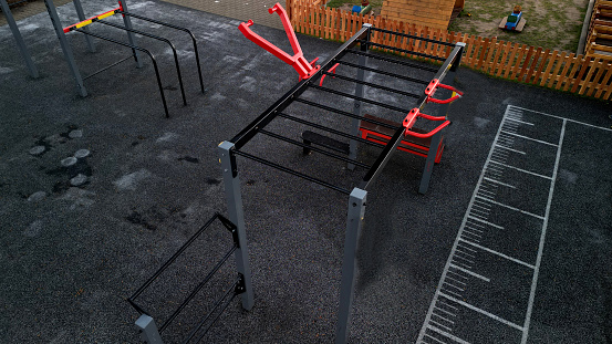 outdoor gym in the yard with stone sandstone wall and flexible rubber floor. sports ground with fitness aids, parallel bars, crossbars, rib tables made of metal . drone, top, point of view, high angle