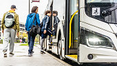 Diverse passengers boarding city bus, wide shot