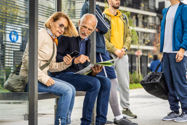 istock Elderly couple reading city map while sitting at bus stop 1457298144