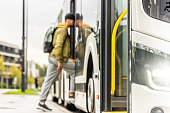 Man boarding bus, selective focus on public transport bumper side