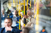 Senior couple standing in bus and holding handrail, medium shot