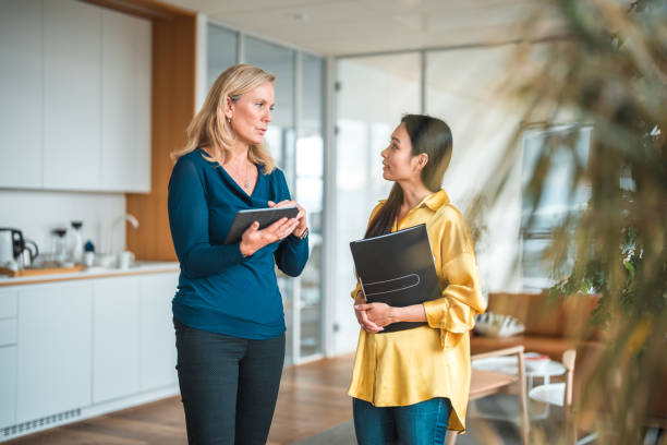 istock Mid Adult Asian and Caucasian Female Entrepreneurs Using Tablet  While Talking 1457298335