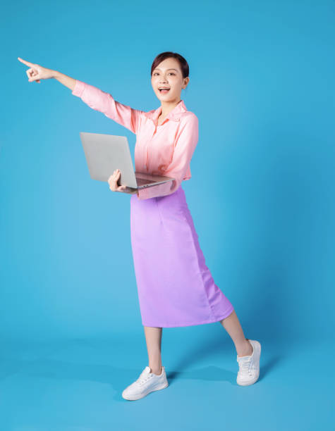 istock Young Asian businesswoman using laptop on blue background 1457305922