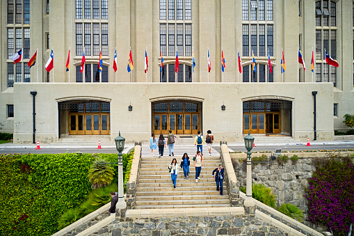 High angle view of diverse college group in casual attire, carrying backpacks, walking down staircase and approaching entrance. Property release attached.