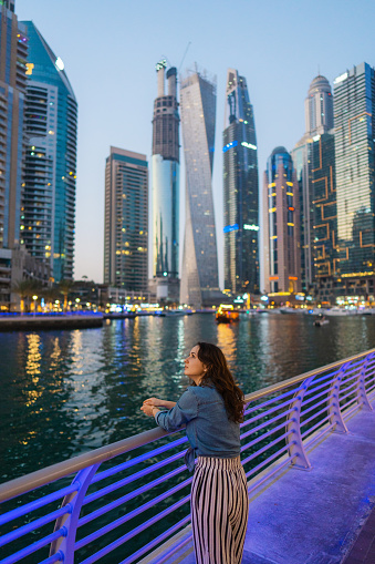 Young Caucasian woman walking in Dubai Marina at sunset