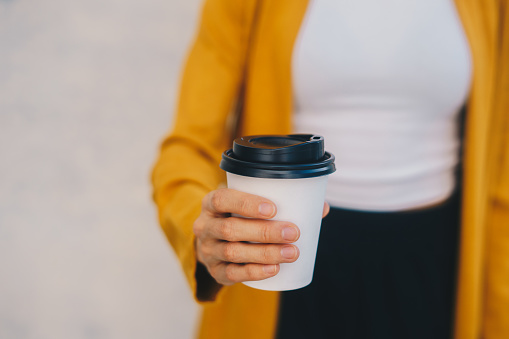 Close up of a woman's hand holding a to go coffee cup