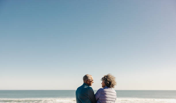 istock Happy elderly couple smiling at each other at the beach 1457313948