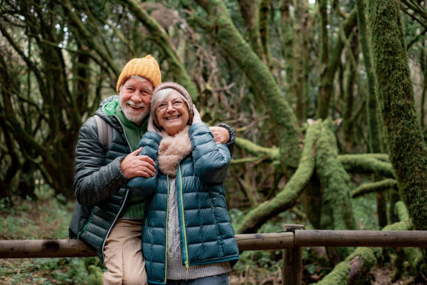 istock Cheerful senior couple enjoying nature outdoors in a mountain forest with moss covered trunks. Joyful elderly couple traveling together in Garajonay national park of La Gomera 1457314304