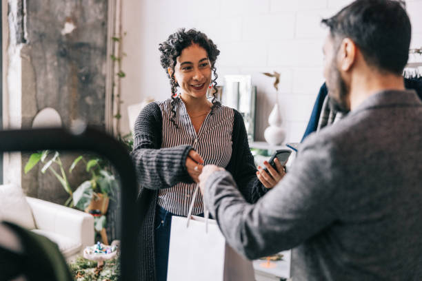 un indien effectuant un paiement mobile dans une boutique de petite entreprise - mid adult men photos et images de collection