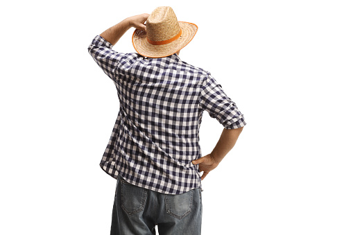 Rear view shot of a farmer looking at the distance and holding his straw hat isolated on white background