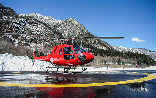 Red helicopter at the wet helipad in the mountains