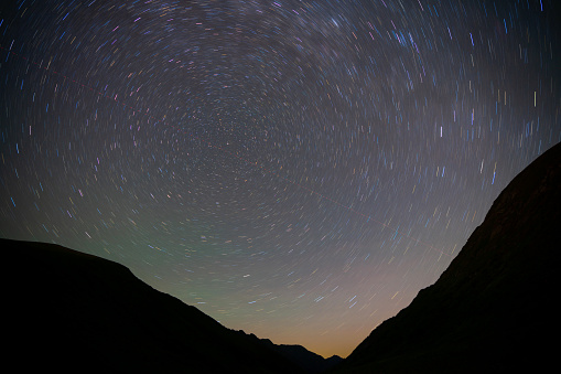 Starry night in the mountains, long exposure, swirl pattern of star trails