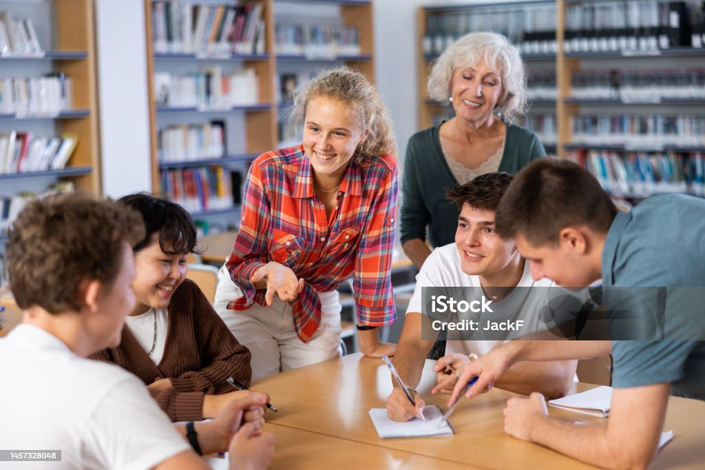Gruppe von Schülern mit einer Lehrerin in der Bibliothek, die etwas diskutiert - Lizenzfrei Lehrkraft Stock-Foto