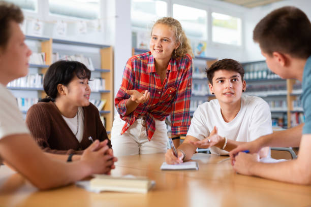 istock Classmates have fun chatting and telling each other in school library 1457328247