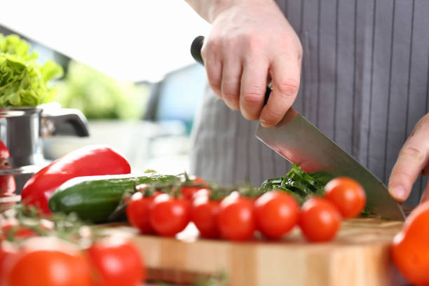 istock Cook cuts tomatoes and cucumbers on cutting board 1457328829