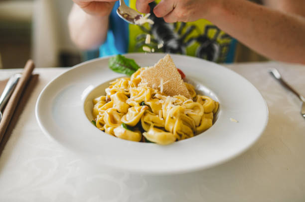 Pouring parmesan on a cheese filled ravioli
