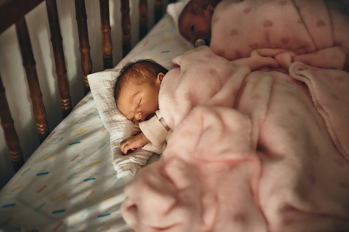 Close-up of a newborn baby girls peacefully sleeping in the crib.