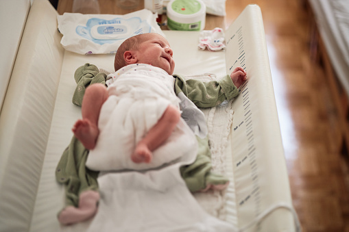 Newborn baby girl is lying on back. Time for diaper change.