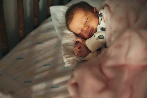 Close-up of a newborn baby girl peacefully sleeping in the crib.