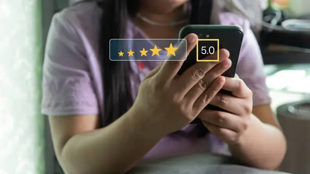 Photo of Customer service satisfaction evaluation concept. Man using smartphone and touching on screen with gold five star rating excellent feedback icon, Rated a very good review.