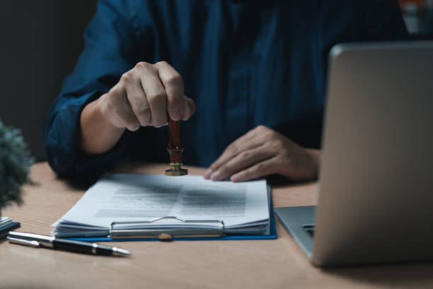 istock Man hand stamping approval signing on document or paperwork contract at desk. 1457332113