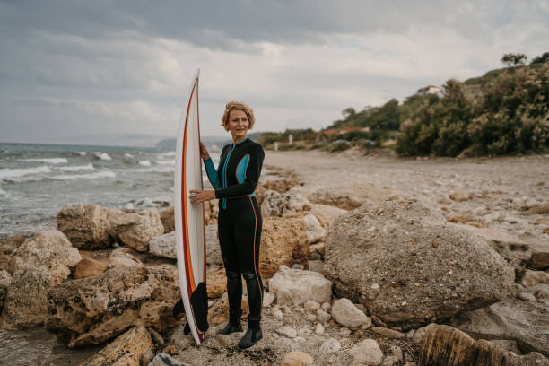 Free Stock Photo of Surfer in wetsuit standing on rocky beach with ...