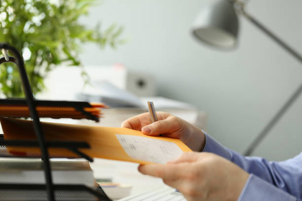 istock Person picks up yellow envelope with mail at workplace 1457333597