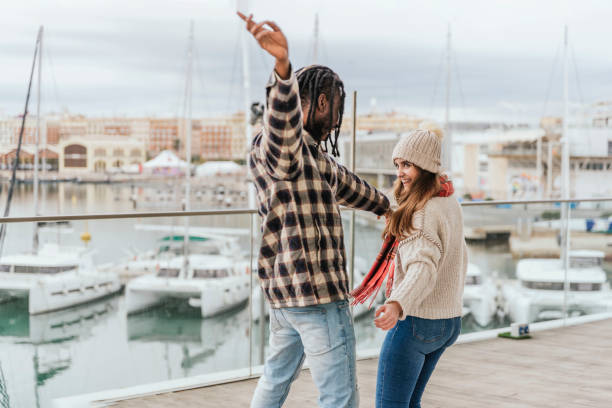 istock multiracial young couple having fun dancing outdoors, harbor on background 1457335668