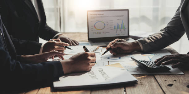 istock Business People Meeting using laptop computer,calculator,notebook,stock market chart paper for analysis Plans to improve quality next month. Conference Discussion Corporate Concept 1457336906