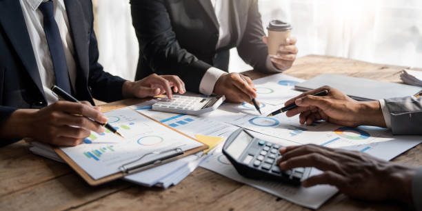 istock Business People Meeting using laptop computer,calculator,notebook,stock market chart paper for analysis Plans to improve quality next month. Conference Discussion Corporate Concept 1457337048