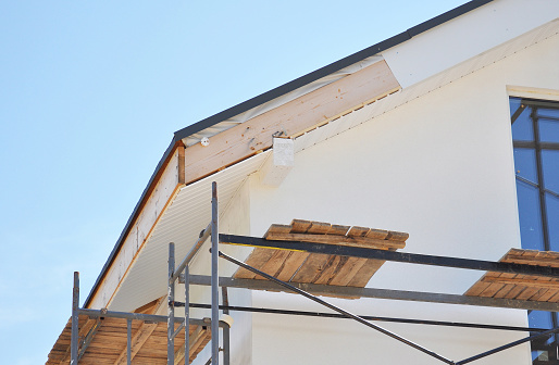 Installing soffit boards and fascias on house eaves roof.