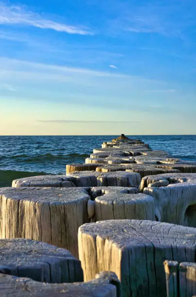 Groynes jut into the horizon in the Baltic Sea. Breakwater at the sea with light waves. Landscape shot at the sea