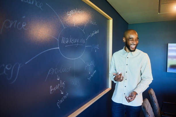 istock Businessman laughing while giving a marketing presentation on an office blackboard 1457337730