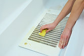 Cleaning a cooker hood filter from fat with a sponge.