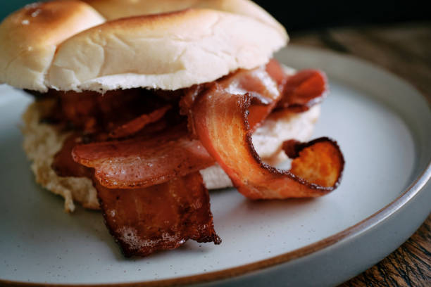 Breakfast bun, soft white roll filled with rashers of smoked bacon. stock photo