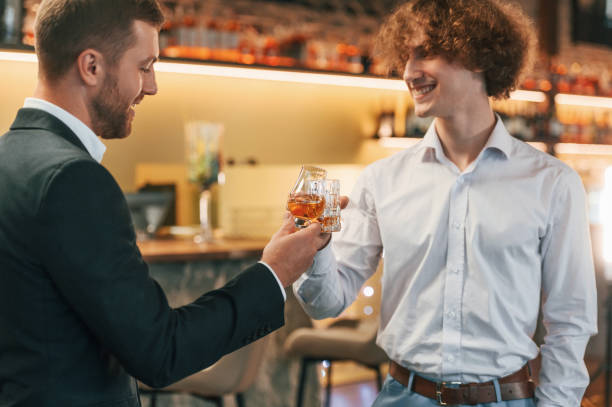 istock Two men knocking glasses in the restaurant. Celebrating event 1457340626