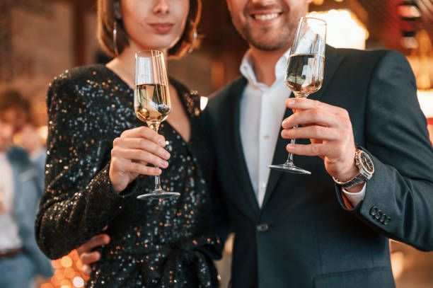 Couple is posing. Group of people in beautiful elegant clothes are celebrating New Year indoors together stock photo
