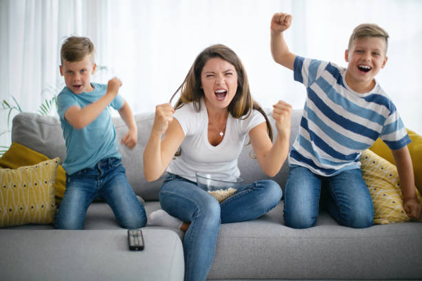テレビでサッカーを見ながら応援する家族。 - domestic life jumping child sofa ストックフォトと画像