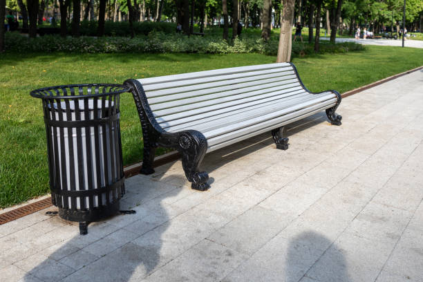 istock Classic park bench and garbage can in a public park on a summer day 1457343956