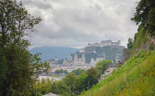 Full panoramic image of Salzburg's famous old town and emerald-colored Salzach River with northern Alpine ridge in the background. Image is composition of 3 separate photos.  