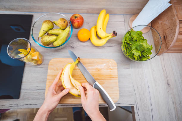 Young woman making fruits smoothies with blender