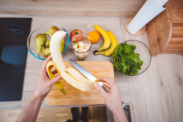 Young woman making fruits smoothies with blender